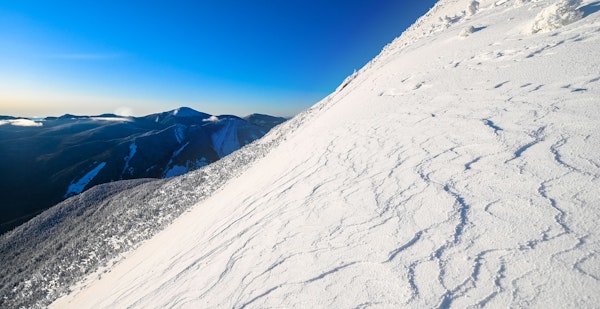 A skier carving turns through powder snow in back country mountains