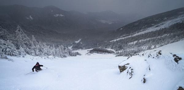 A skier carving turns through powder snow in back country mountains